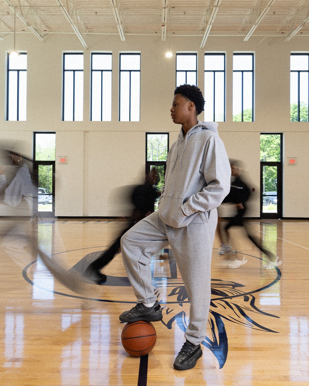 Student in the grey DAA sweatsuit standing on a basketball in the school gym