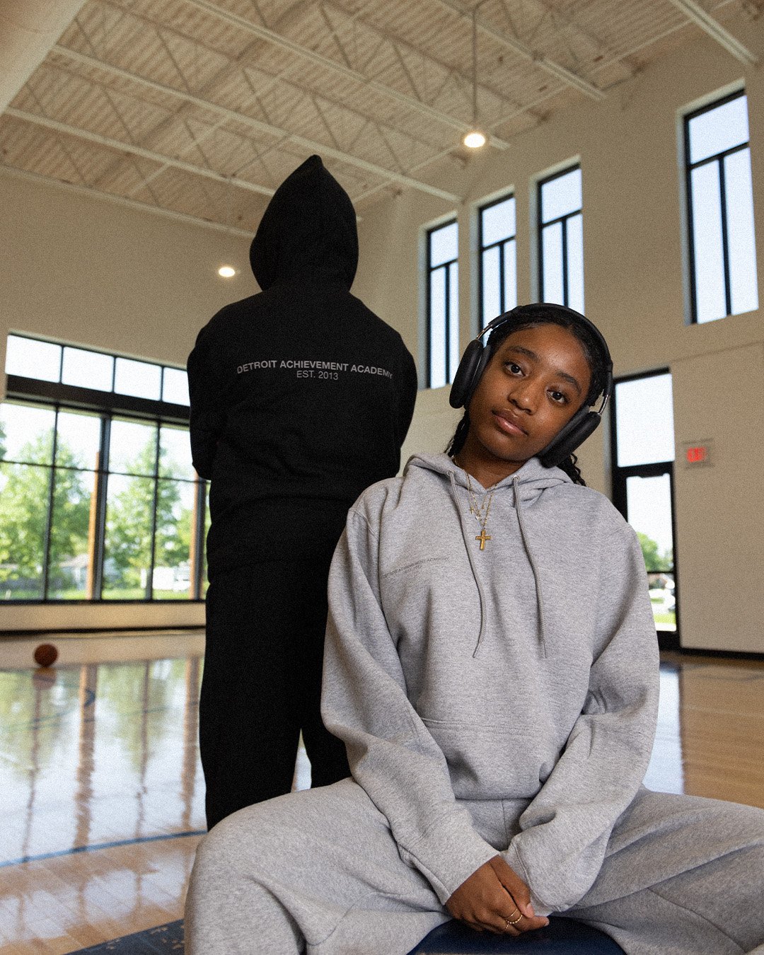 Two students in black and grey Detroit Achievement Academy Est. 2013 hoodies in the gym