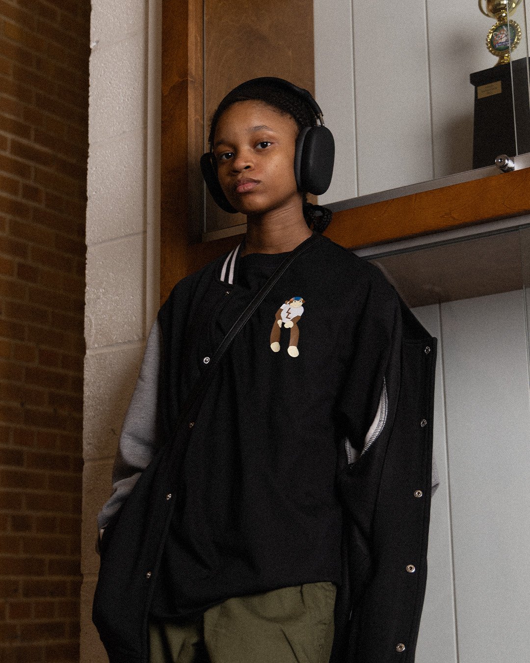 Student in headphones wearing the varsity jacket over a tee with a monkey graphic