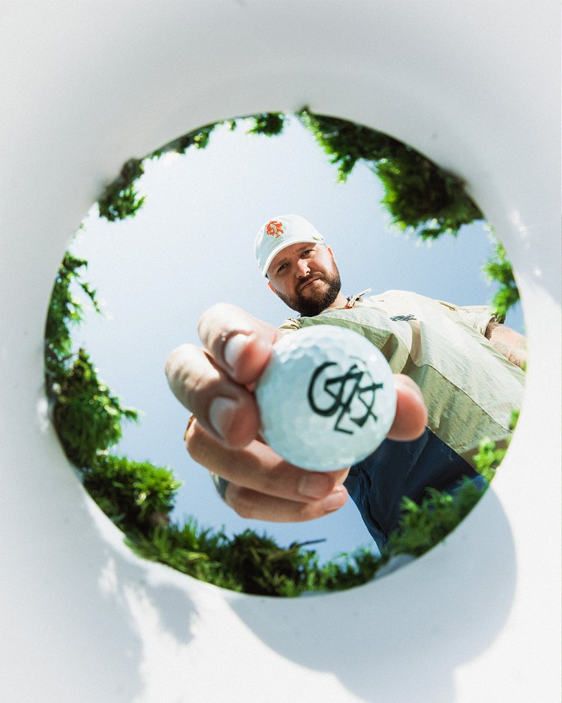 SANA Golf campaign: looking up from inside the cup at a golfer holding a SANA ball