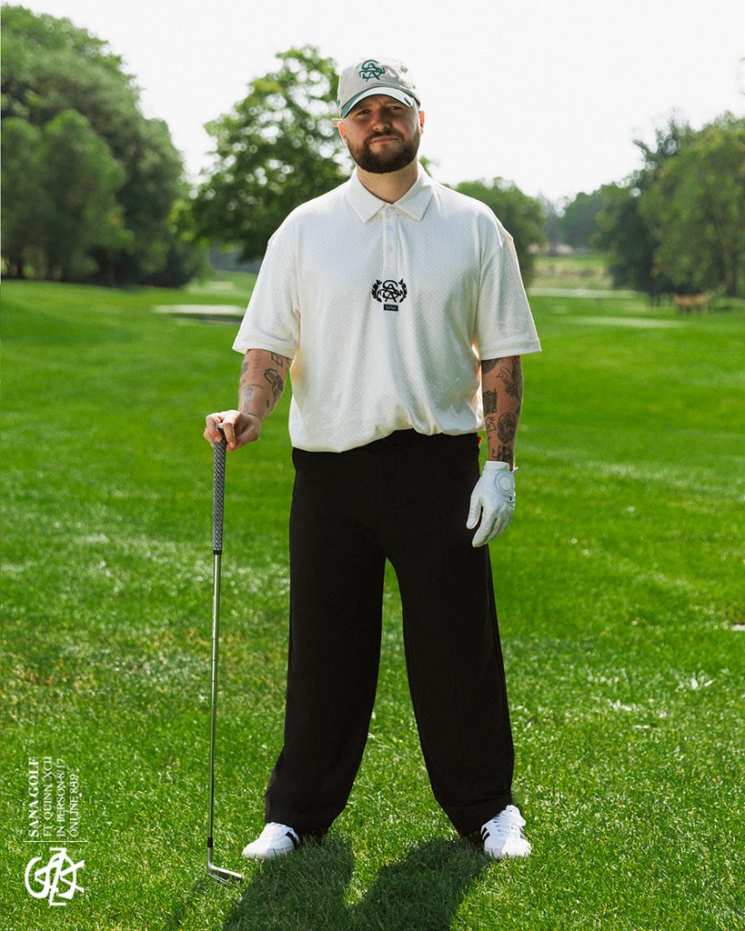 Cream SANA crest polo with black trousers, holding an iron